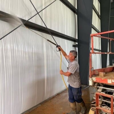 Employee Actively Pressure Washing Storage Space Walls in Chattanooga TN by QualityPRO Power Washing