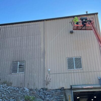 Employee in Lift Cleaning Metal Building in Chattanooga TN by QualityPRO Power Washing