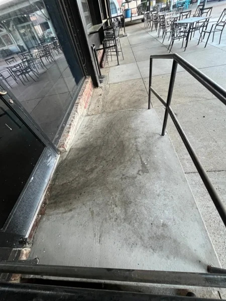 Commercial concrete pressure washing completed at a building entrance, removing heavy dirt and grime buildup to restore a cleaner, brighter, and safer walkway.