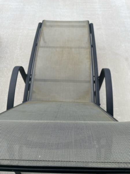 Outdoor lounge chair with a metal frame and gray mesh fabric, viewed from above on a concrete surface.