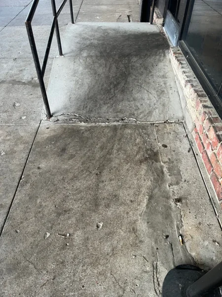Commercial concrete pressure washing completed at a building entrance, removing heavy dirt and grime buildup to restore a cleaner, brighter, and safer walkway.