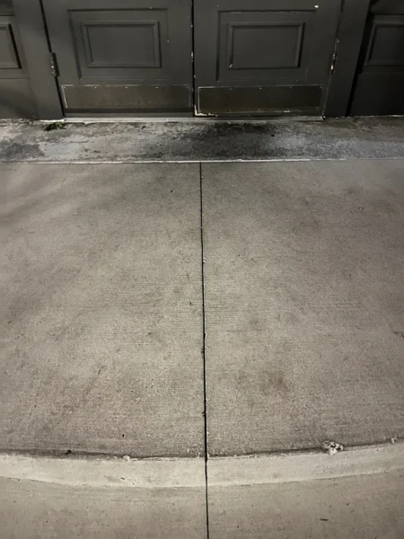 Commercial concrete pressure washing completed at a building entrance, removing heavy dirt and grime buildup to restore a cleaner, brighter, and safer walkway.