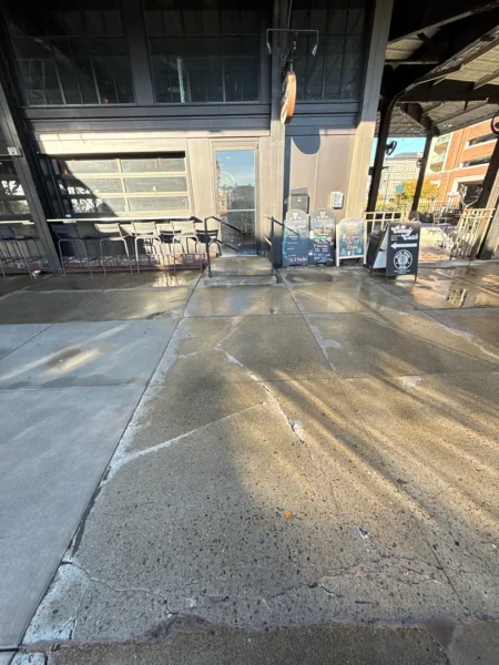Commercial concrete pressure washing completed at a building entrance, removing heavy dirt and grime buildup to restore a cleaner, brighter, and safer walkway.
