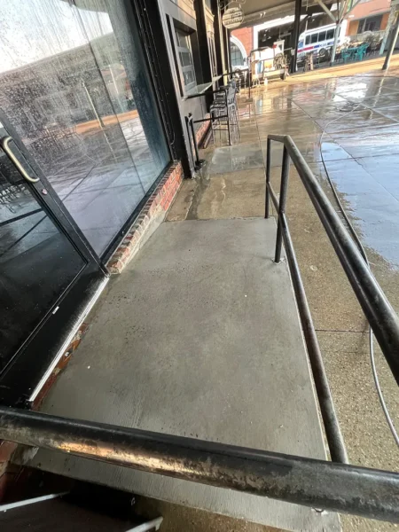 Commercial concrete pressure washing completed at a building entrance, removing heavy dirt and grime buildup to restore a cleaner, brighter, and safer walkway.