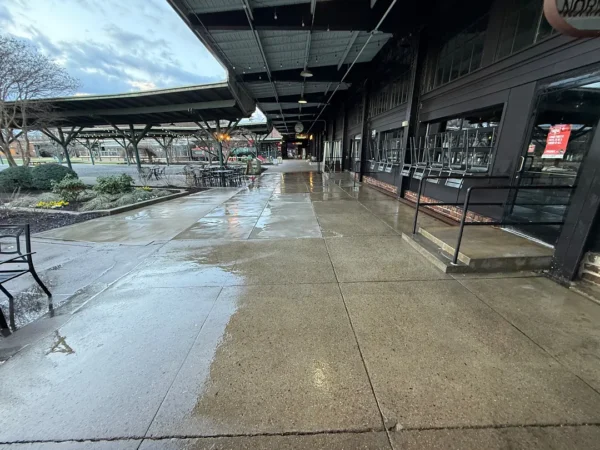 Commercial concrete pressure washing completed at a building entrance, removing heavy dirt and grime buildup to restore a cleaner, brighter, and safer walkway.
