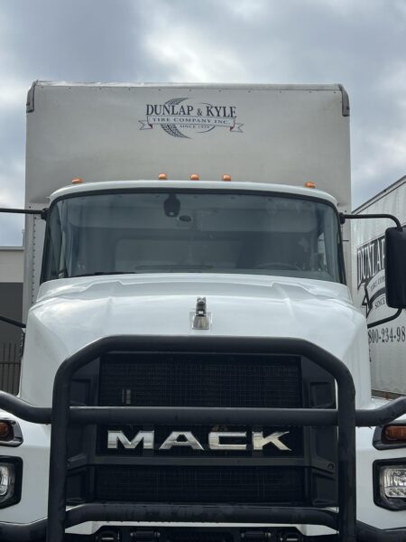 Front view of a white Mack semi-truck with a box trailer displaying the Dunlap & Kyle Tire Company logo on the trailer.
