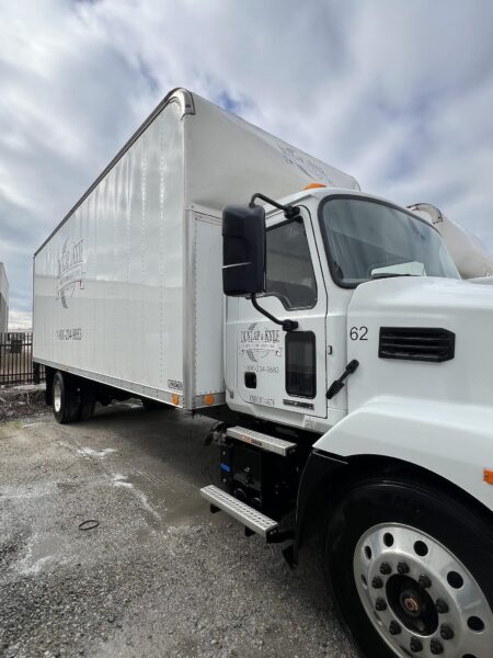 White semi-truck with a large box trailer, Dunlap & Kyle Tire Company logo on the side, parked on gravel.