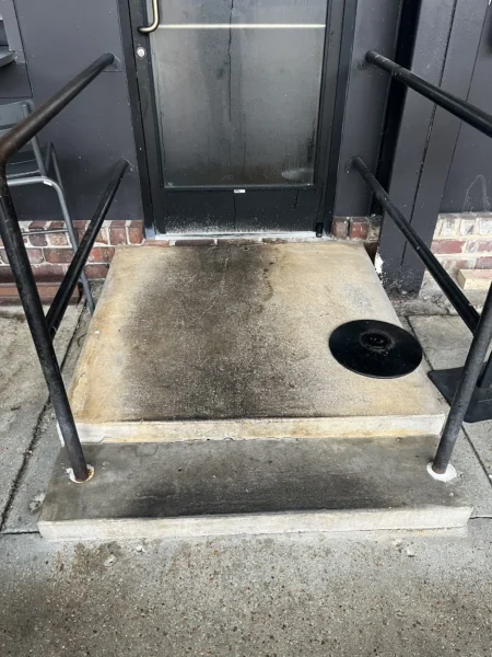 Commercial concrete pressure washing completed at a building entrance, removing heavy dirt and grime buildup to restore a cleaner, brighter, and safer walkway.