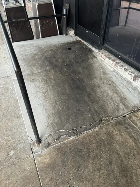 Commercial concrete pressure washing completed at a building entrance, removing heavy dirt and grime buildup to restore a cleaner, brighter, and safer walkway.