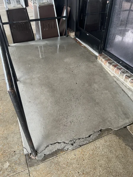 Commercial concrete pressure washing completed at a building entrance, removing heavy dirt and grime buildup to restore a cleaner, brighter, and safer walkway.