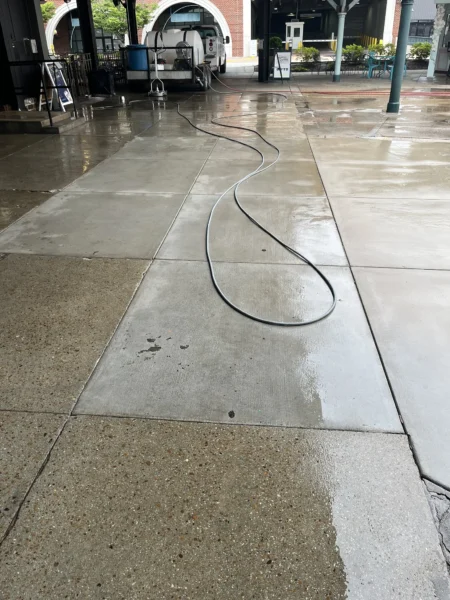 Commercial concrete pressure washing completed at a building entrance, removing heavy dirt and grime buildup to restore a cleaner, brighter, and safer walkway.