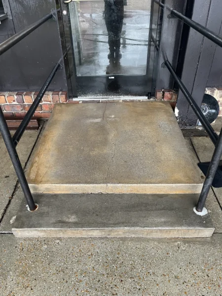 Commercial concrete pressure washing completed at a building entrance, removing heavy dirt and grime buildup to restore a cleaner, brighter, and safer walkway.