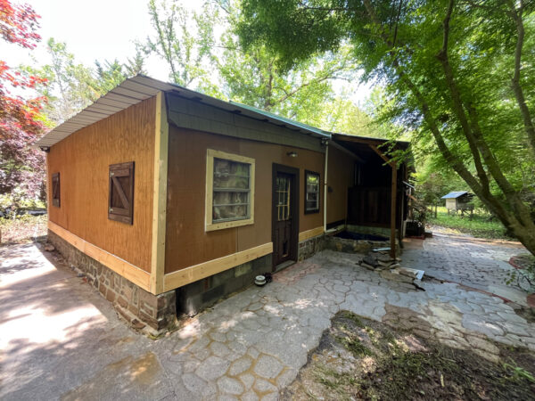 This project involved the soft washing of a one-story residence's exterior, its driveway and walkway pavers, and a stone fountain, alongside the cleaning of a commercial metal roof, to remove organic growth and restore the appearance of all surfaces in McDonald.