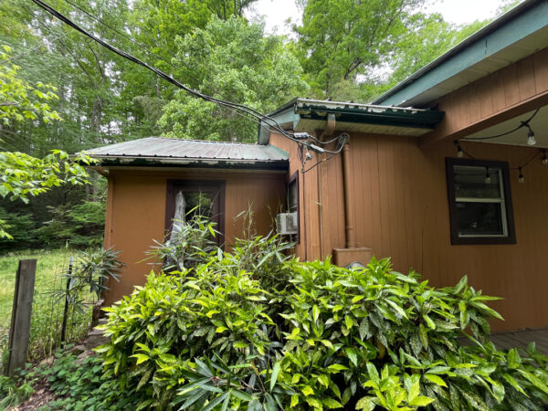 This project involved the soft washing of a one-story residence's exterior, its driveway and walkway pavers, and a stone fountain, alongside the cleaning of a commercial metal roof, to remove organic growth and restore the appearance of all surfaces in McDonald.