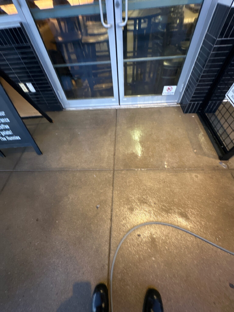 The front patio concrete at Milk and Honey was professionally restored through a multi-step process involving site protection, specialized detergent application, targeted pressure washing, and a final rinse to remove organic growth and grease.