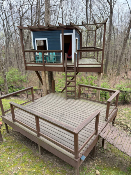 The work performed consists of soft washing and rinsing the primary structure's exterior surfaces, three rear decks, a treehouse with its decks and bridges, and surface cleaning the concrete flatwork, all backed by a one-year warranty against mold and mildew regrowth.