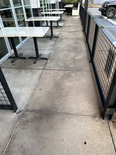 The front patio concrete at Milk and Honey was professionally restored through a multi-step process involving site protection, specialized detergent application, targeted pressure washing, and a final rinse to remove organic growth and grease.