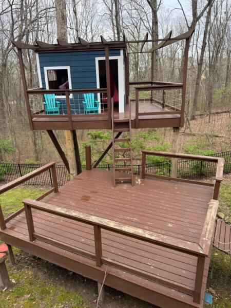 The work performed consists of soft washing and rinsing the primary structure's exterior surfaces, three rear decks, a treehouse with its decks and bridges, and surface cleaning the concrete flatwork, all backed by a one-year warranty against mold and mildew regrowth.