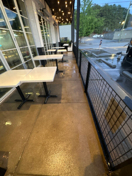The front patio concrete at Milk and Honey was professionally restored through a multi-step process involving site protection, specialized detergent application, targeted pressure washing, and a final rinse to remove organic growth and grease.