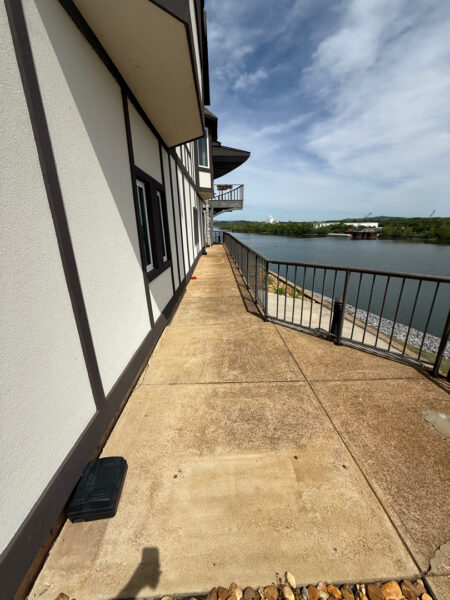 This Chattanooga project utilized surface and soft washing techniques to deep clean the rear walkway, under-deck concrete, and 1896 bar patio while specifically removing red clay stains from the chimney and retaining walls.
