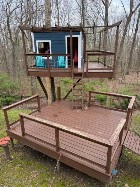 The work performed consists of soft washing and rinsing the primary structure's exterior surfaces, three rear decks, a treehouse with its decks and bridges, and surface cleaning the concrete flatwork, all backed by a one-year warranty against mold and mildew regrowth.