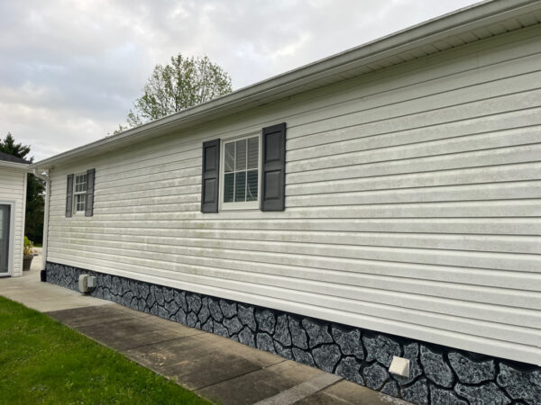 Professional soft wash exterior cleaning will be performed on the main house, porches, and three garage buildings, targeting all vertical surfaces and roofline components to remove organic growth and debris with a one-year warranty.