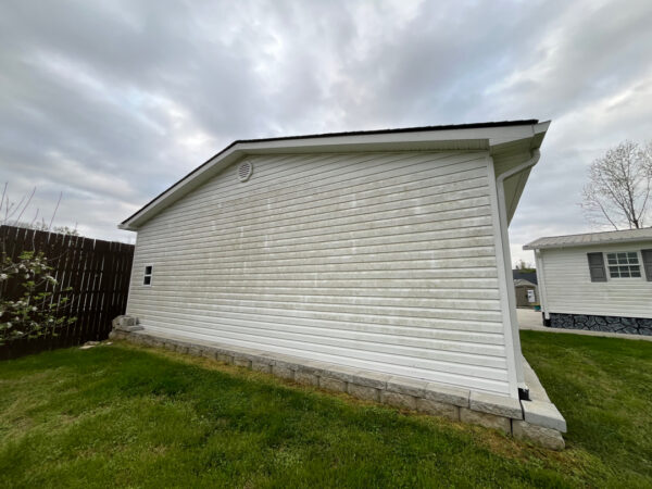 Professional soft wash exterior cleaning will be performed on the main house, porches, and three garage buildings, targeting all vertical surfaces and roofline components to remove organic growth and debris with a one-year warranty.