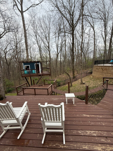The work performed consists of soft washing and rinsing the primary structure's exterior surfaces, three rear decks, a treehouse with its decks and bridges, and surface cleaning the concrete flatwork, all backed by a one-year warranty against mold and mildew regrowth.