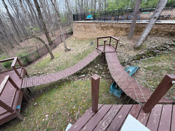 The work performed consists of soft washing and rinsing the primary structure's exterior surfaces, three rear decks, a treehouse with its decks and bridges, and surface cleaning the concrete flatwork, all backed by a one-year warranty against mold and mildew regrowth.