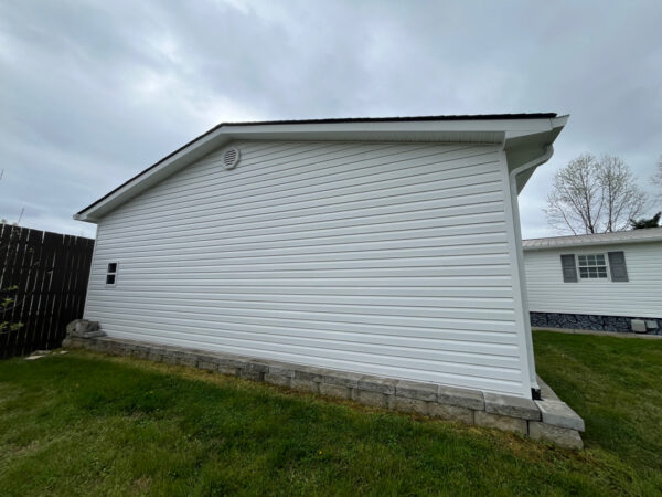 Professional soft wash exterior cleaning will be performed on the main house, porches, and three garage buildings, targeting all vertical surfaces and roofline components to remove organic growth and debris with a one-year warranty.