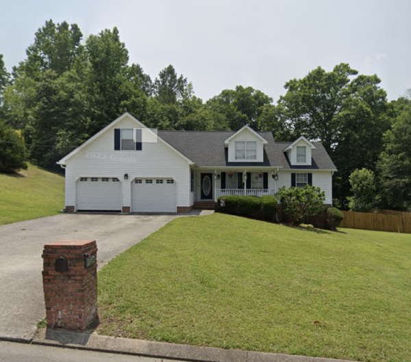 White single-family home with a two-car garage, front porch, and a large grassy front yard.