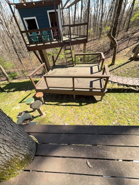 The work performed consists of soft washing and rinsing the primary structure's exterior surfaces, three rear decks, a treehouse with its decks and bridges, and surface cleaning the concrete flatwork, all backed by a one-year warranty against mold and mildew regrowth.