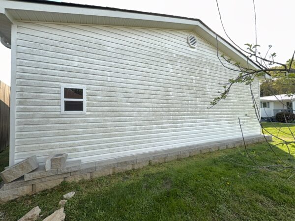 Professional soft wash exterior cleaning will be performed on the main house, porches, and three garage buildings, targeting all vertical surfaces and roofline components to remove organic growth and debris with a one-year warranty.