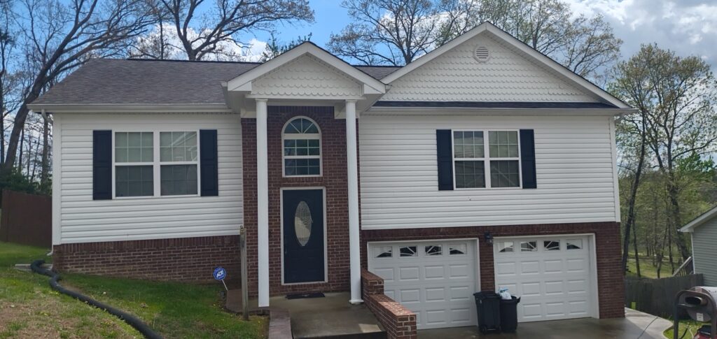 Front view of a two-story house with brick lower level, white siding, blue shutters, and a two-car garage.