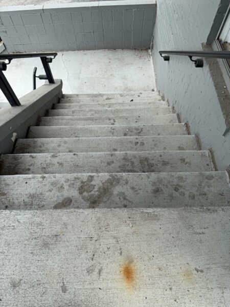 This project involved an after-hours exterior cleanup of a commercial parking area in Chattanooga, which included removing leaf debris and weeds, pressure washing concrete surfaces with detergents to eliminate mold and grime, and applying specialized treatments to remove black spray paint from concrete pads and steps.