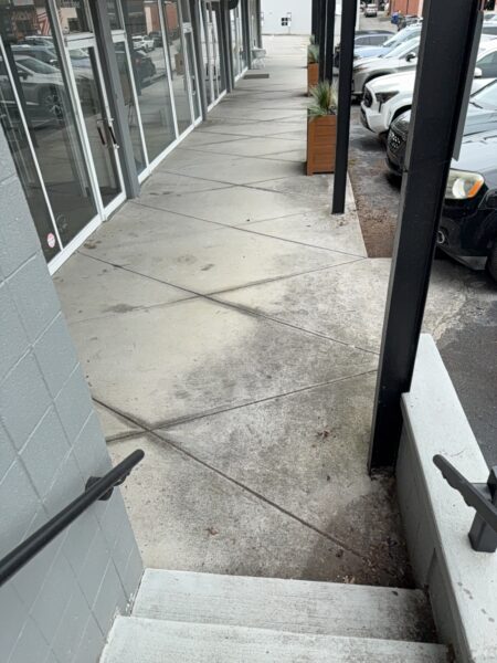 This project involved an after-hours exterior cleanup of a commercial parking area in Chattanooga, which included removing leaf debris and weeds, pressure washing concrete surfaces with detergents to eliminate mold and grime, and applying specialized treatments to remove black spray paint from concrete pads and steps.