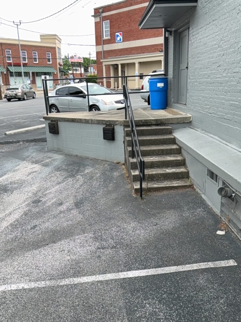 This project involved an after-hours exterior cleanup of a commercial parking area in Chattanooga, which included removing leaf debris and weeds, pressure washing concrete surfaces with detergents to eliminate mold and grime, and applying specialized treatments to remove black spray paint from concrete pads and steps.
